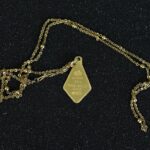Collar de oro amarillo con dije rectangular tipo lingote grabado “SUISSE 2.5g FINE GOLD 999.9”, acompañado de cadena de eslabones redondeados con detalles de esferas intercaladas