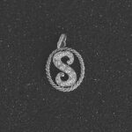 Dije de oro blanco 18K con letra “S” pavé de diamantes dentro de aro trenzado